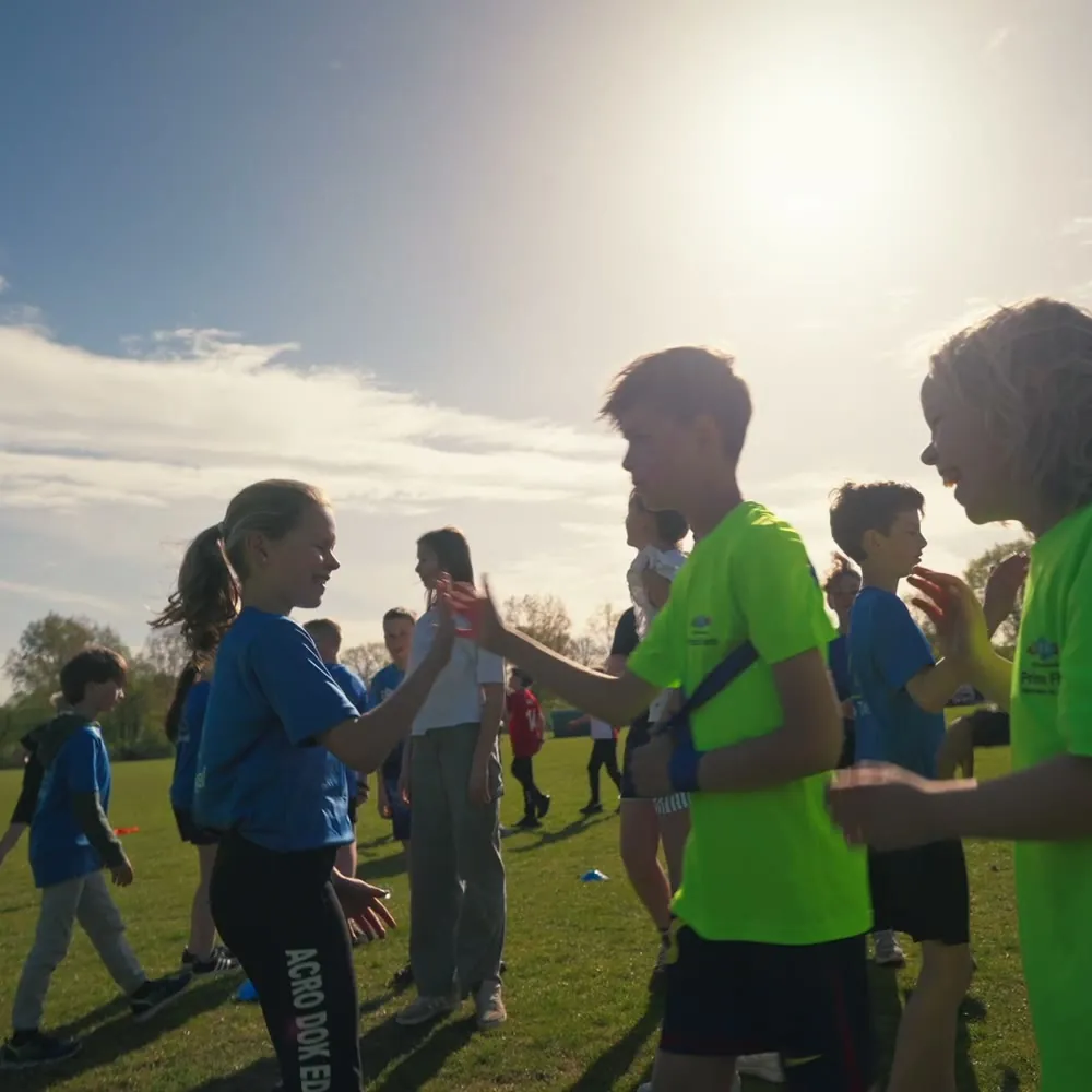 Trainer en kinderen samen op het sportveld